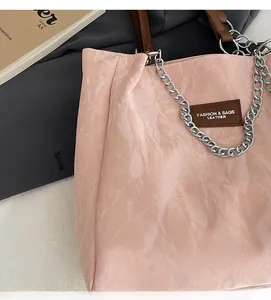 Détail du grand cabas rose froissé avec chaîne argentée et écusson logo en cuir marron