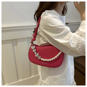 Detail of rose red half-moon bag with decorative pearl heart chain and leather knot strap
