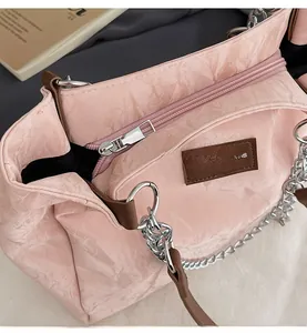 Gros plan du sac cabas en cuir froissé avec chaîne argentée et poignée en cuir marron