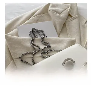 Detail of white PU mini bag featuring a crystal double bow and silver box chain strap