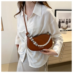 Detail of brown half-moon leather shoulder bag with silver heart and pearl charms