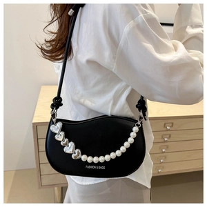 Black half-moon saddle bag featuring heart metal charms and pearl chain accessory