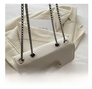 Detail of white leather shoulder bag featuring a sparkling crystal bow and silver metal chain