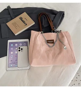 Détail d'un sac cabas plissé rose avec chaîne en métal et poignée en cuir et étiquette