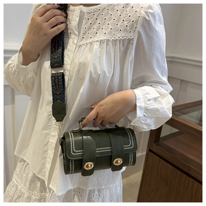 Detail of dark green square bag featuring rivet edges and ethnic style embroidery strap
