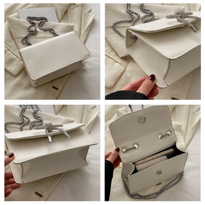 Detail view of white crossbody bag with rhinestone bow and silver chain strap