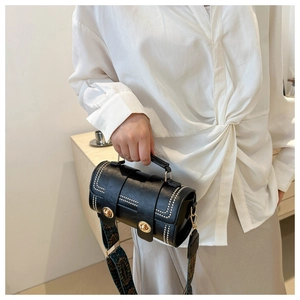 Detail of black leather cylindrical bag with gold studs and ethnic jacquard strap