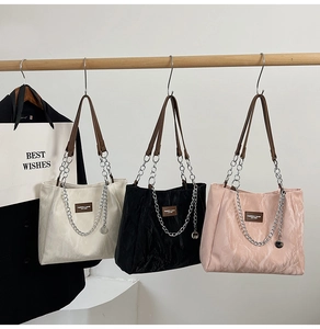 Gros plan de trois sacs fourre-tout colorés avec chaînes et poignées en cuir suspendus