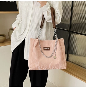 Détail du sac cabas rose clair avec chaîne argentée et anses en cuir marron pour femme