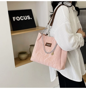 Sac fourre-tout plissé rose avec chaîne argentée et poignée en cuir porté à l'épaule