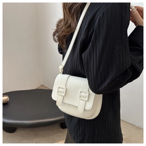 Detail of white PU leather saddle bag with gold buckles and adjustable shoulder strap