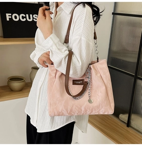 Détail d'un cabas rose clair avec texture froissée et chaîne argentée décorative