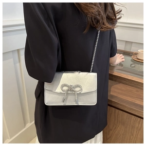 Détail du sac à chaîne argenté avec nœud en cristal et fini satiné sur modèle