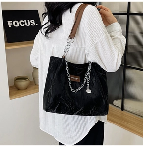 Détail du cabas noir avec texture froissée et bandoulière mixte cuir et chaîne