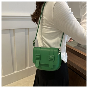 Detail view of emerald green saddle bag with double square buckles and adjustable strap