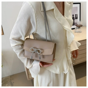 Détail d'un sac à chaîne élégant avec nœud en strass et pompons porté par un mannequin