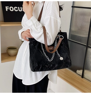 Détail du sac cabas noir froissé avec chaîne argentée et bandoulière en cuir marron