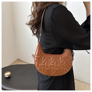 Detail of dark brown crescent hobo bag with geometric embossed texture and gold buckle
