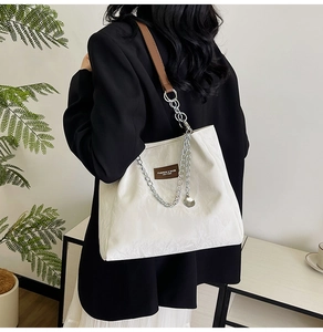 Détail d'un grand cabas blanc avec chaîne argentée et bandoulière en cuir marron