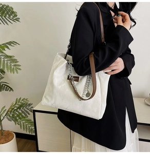 Détail du sac cabas blanc avec texture plissée, lanières marron et chaîne en métal argenté