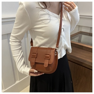 Detailed view of a brown leather saddle bag with two buckled straps on a model