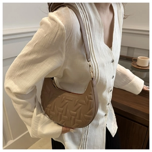 Chic brown crescent shoulder bag with geometric embossing shown on a female model