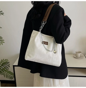 Détail du sac cabas blanc cassé avec chaîne argentée et patch en cuir pour femme