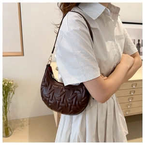 Close-up of a dark brown crescent bag featuring geometric embossed texture on shoulder