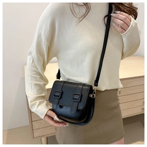 Detail of a black faux leather saddle bag worn by a model with adjustable straps