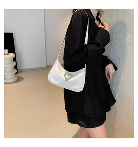 Close-up of a white crescent shoulder bag with a sparkling heart-shaped crystal buckle