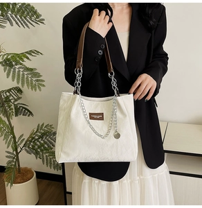 Détail du sac cabas blanc texturé avec anses en cuir marron et chaîne argentée