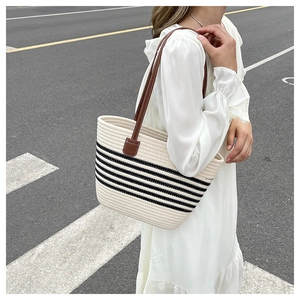 Detail of handwoven cream tote bag with black stripes and brown leather straps