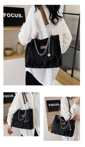 Détail du sac cabas noir avec chaîne argentée, brides brunes et texture plissée