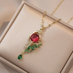 Collier pendentif paon doré élégant avec zircons rouges et verts sur un coffret à bijoux