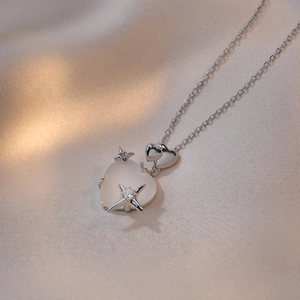 Detail of cat eye heart pendant with starburst and zircon on silk background