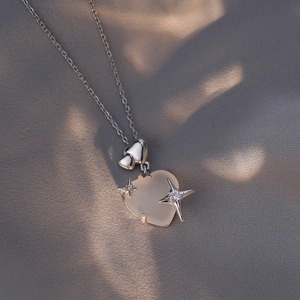 Elegant cat eye stone heart pendant necklace with silver chain on silk background