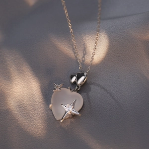 Cat eye stone heart necklace with starburst detail on elegant grey silk background