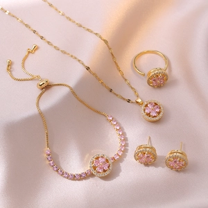 Detailed set of gold-plated jewelry with pink zircon flower pendants on silk