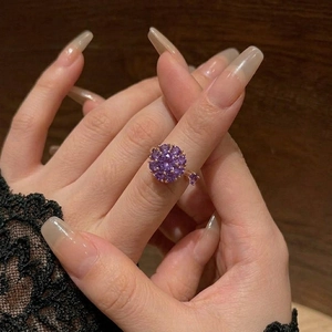 Elegant rose gold flower ring featuring purple gemstones in a sparkling sunburst cluster