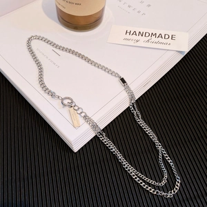 Double-layered silver Cuban chain necklace with a black charm and branded logo tag