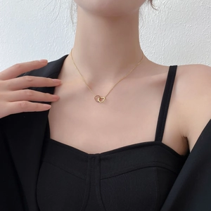 Close-up of interlocking gold heart necklace pendant worn by a model on a fine chain