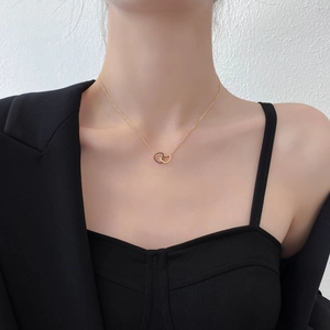 Detailed view of intertwined double heart pendant necklace in gold finish on model