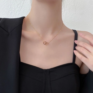 Close-up of golden interlocking double heart pendant on a delicate chain necklace