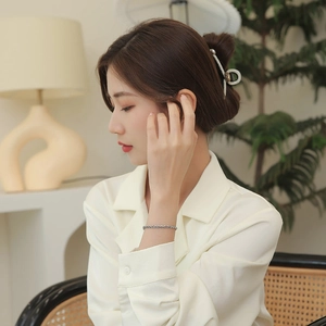 Minimalist silver chain bracelet for women on model in cozy home setting with warm lighting