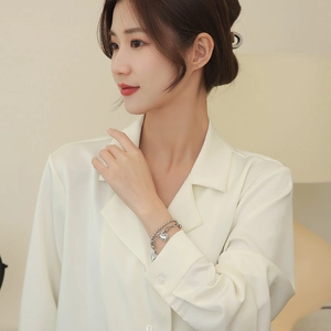 Double-layered silver heart bracelet with bead and link chains worn by a female model