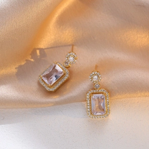 Élégantes boucles d'oreilles en titane doré avec zircons roses sur satin champagne