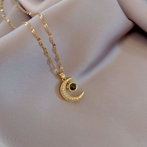 Gold crescent moon projection necklace with micro-pave crystals and black center stone