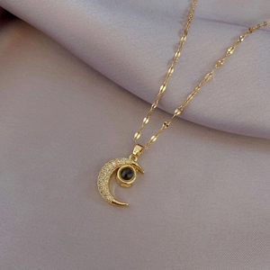 Detailed view of gold crescent moon necklace with zircon inlay and black projection stone