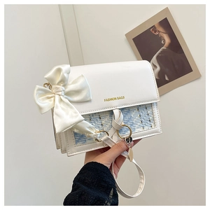 Detail of tweed crossbody bag with a large white satin bow and gold buckle accents