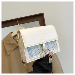 Detail of cream white crossbody bag with blue tweed patchwork and golden chain strap